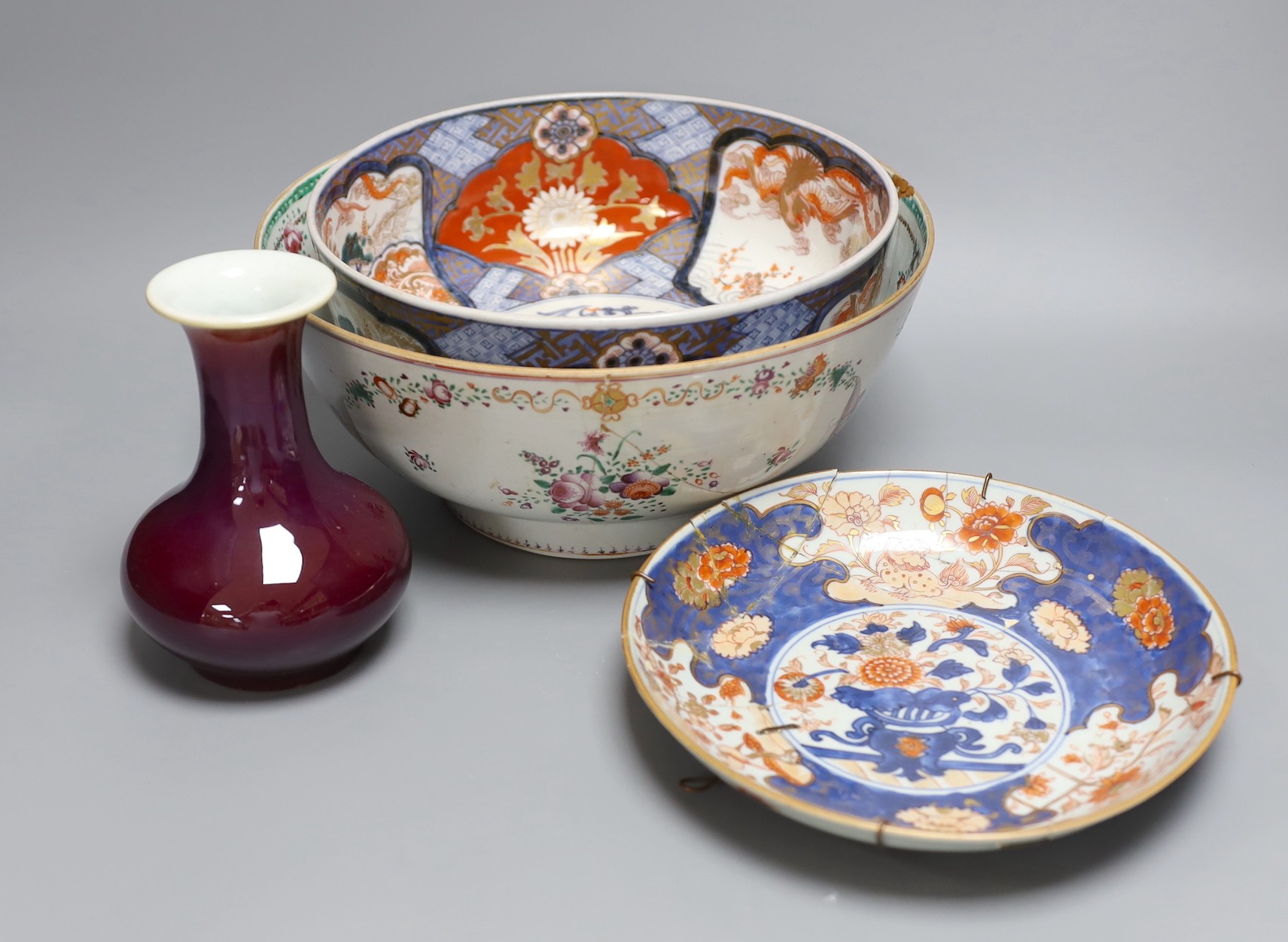 An 18th century Japanese Imari dish (af), another Imari dish, an 18th century Chinese export bowl (af) and a Chinese sang de boeuf vase, diameter of largest bowl 29cm